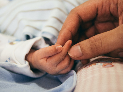 A parent holds a babys hand